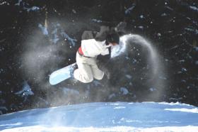 A snowboarder displays a backside grab at Soll.