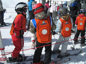 Young skiers wear magnestick vests.