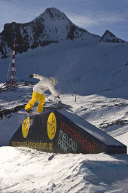 A snowboarder railslides in the Kitzsteinhorn Mellow Park.