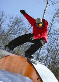 An Indianhead snowboarder rail slides. 