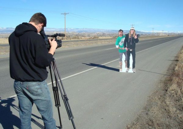 The cardboard clones of Jonny Van Easle and Lou Irons hitchhike to the next resort.