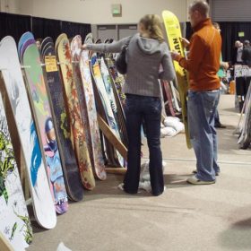 A couple examining snowboards at Seattle SkiFever.